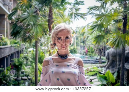Woman is posing in a tropical garden of Bali island.