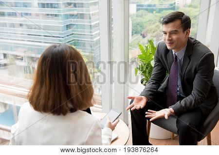 Smiling confident businessman talking with client in ofiice lounge