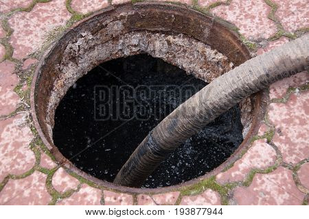 man pumping sewage from the drain hole.