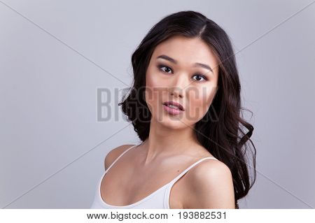 Portrait of a beautiful asian woman with makeup and light curls.