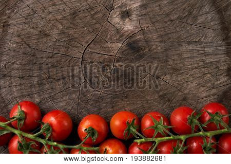 Close-up of Tomatoes. View from above of a Cherry tomatoes. Fresh grape tomatoes on a branch on wooden background. Top view with copy space. Healthy eating and detox concept.