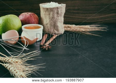 Bakery background comprise with apples wheat flour egg and cinnamon on granite table with copy space.Prepare ingredient for baking apple cake on granite background. Bakery background concept.