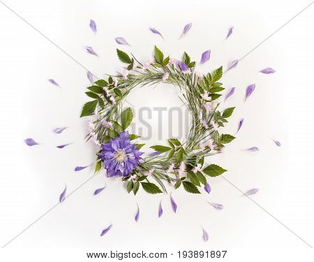 Frame wreath with white and pink flowers branches leaves and petals and big purple flower of Clematis. Flat lay overhead view.