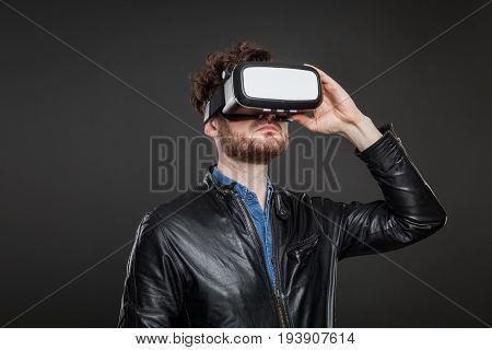 Man in a black leatherjacket wearing virtual reality goggles