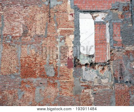 part of old derelict brick wall with several different bricks and cement patches after demolition work