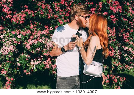 Couple in park eating ice cream cones, posing on camera