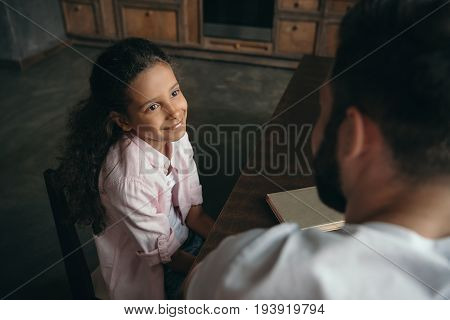 Adorable Pre-adolescent Girl Talking With Father While Sitting At Table
