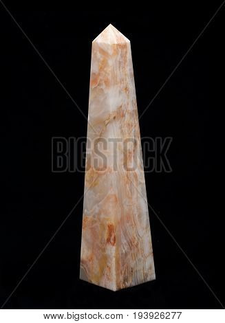 Polished multicolor carved onyx obelisk on black background