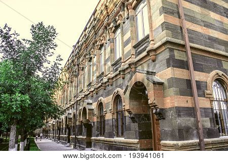 View from the side on the facade of old building of multi-colored tufa stone with carved archescolumns and cornices