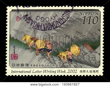 JAPAN - CIRCA 2002: A stamp printed in Japan shows travellers surprised by sudden rain, painting by Utagawa Hiroshige, international letter-writing week 2002, circa 2002