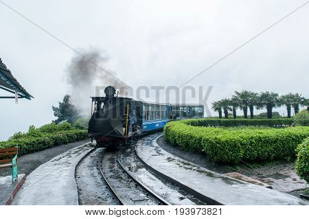 May 01,2017.The Darjeeling Himalayan Railway, also known as the Toy Train, is a 2 ft narrow gauge railway,is entering to the Batasia loop,Darjeeling, west bengal, India. after a heavy rainfall.