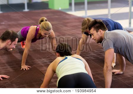 fitness, sport, exercising, training and healthy lifestyle concept - group of people doing straight arm plank in gym