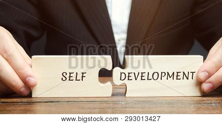 Businessman Collects Puzzles With The Word Self-development. Concept Of New Business Skills And Moti