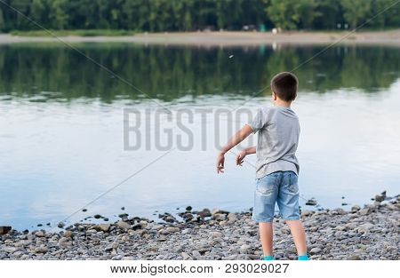 A Child, A Teenager, On A Stony Shore Throws Stones Into The River, Lake