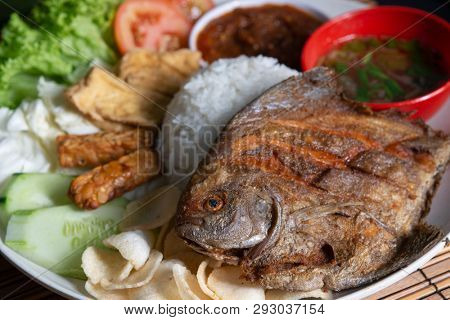 Fried pomfret fish and rice, popular traditional Malay or Indonesian local food.