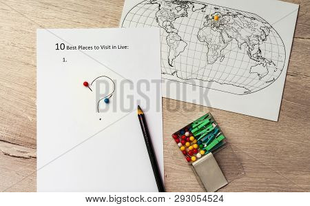 The Inscription On A White Shee Ten Best Plases To Visit In Live. On A Wooden Background With World 