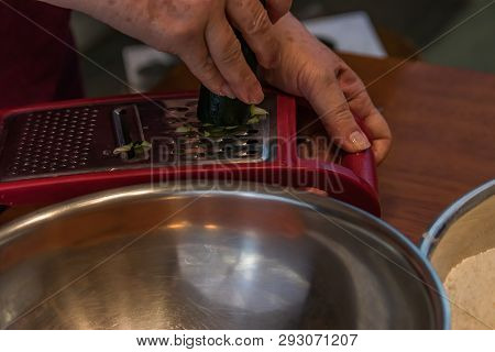 Using A Red Cheese Grater To Shredd A Zucchini