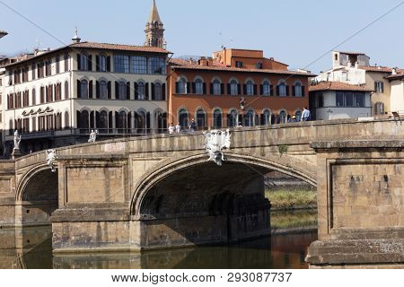 FLORENCE, ITALY - AUGUST 8, 2018: People on the Ponte Santa Trinita bridge across Arno river. It is the oldest elliptic arch bridge in the world, created in 1569 by Bartolomeo Ammannati