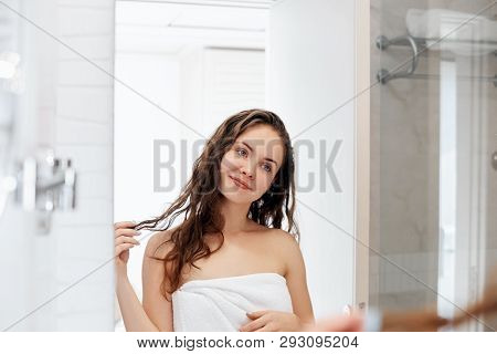 Hair And Body Care. Woman Touching Hair And Smiling While Looking In The Mirror.portrait Of Happy Gi
