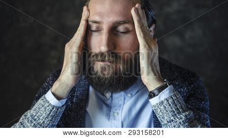 Portrait Of Pensive Bearded Man In Blue Shirt And Cardigan With Eyes Closed, Holding His Temples. Tr