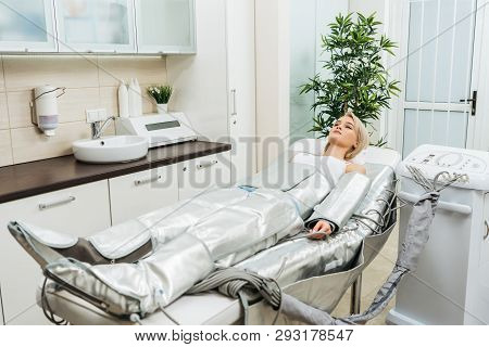 Blonde Girl Lying On Beauty Couch During Pressotherapy Session In Clinic