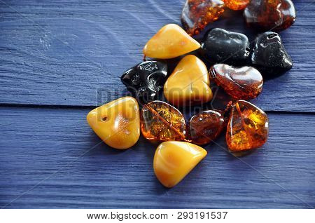 Old Beads Made Of Polished Amber Stones Of Different Colors On The Blue Wooden Background, Selective