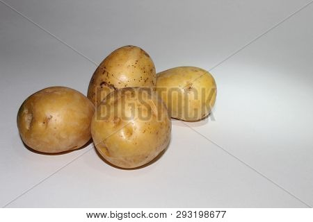 Four Potatoes Lie On A White Background In A Pile