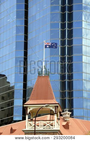 Australian Flag Flying On Flagpole At The Roof Of An Old Fashioned Building In Front Of An Office Bu