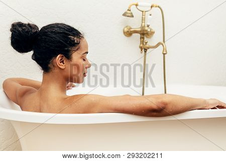 Side View Of Female Relaxing In Bathtub With Her Eyes Closed