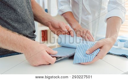 Tailor and customer choosing material for bespoke shirt from pattern book