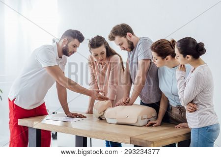 Group Of People With Handsome Instructor Performing Cpr On Dummy During First Aid Training