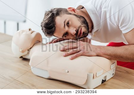 Man Looking At Camera While Practicing Cpr Technique On Dummy During First Aid Training