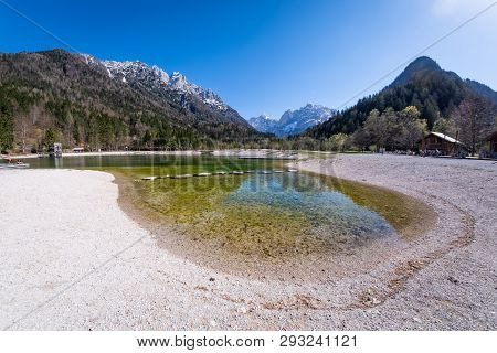 Beach On Lake Jasna With Mountains Razor And Prisojnik On The Horizont In Slovenia