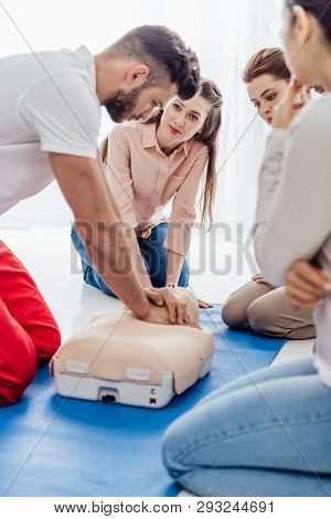 Selective Focus Of Instructor Performing Cpr On Dummy During First Aid Training With Group Of People