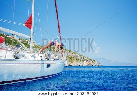 Girl Jump In Sea Of Sailing Yacht On Summer Cruise. Travel Adventure, Yachting With Child On Vacatio