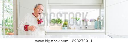 Wide angle perspective of handsome senior man at home touching mouth with hand with painful expression because of toothache or dental illness on teeth. Dentist concept.