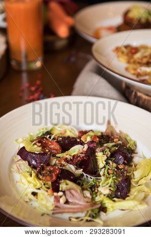 Healthy vegeterian food on brown wood board. Salad from beet with dried tomatoes and cabbage