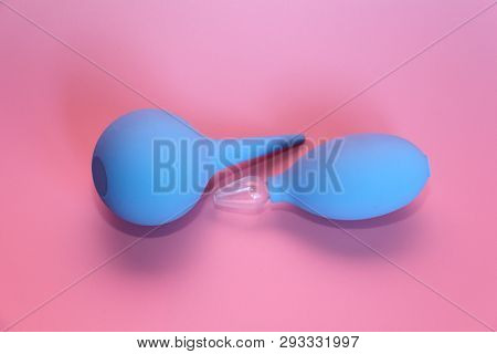 Blue Enema With A Soft Tip. Blue Nasal Aspirator With Glass Tip. Pink Background.
