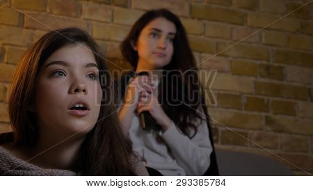 Closeup Shoot Of Two Young Cute Girls Watching Tv Together Witn Shocked Facial Expressions While Res