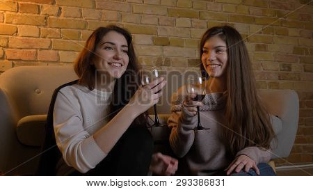 Closeup Portrait Of Two Young Pretty Women Watching A Movie Tv Chilling With Wine Laughing Cheerfull