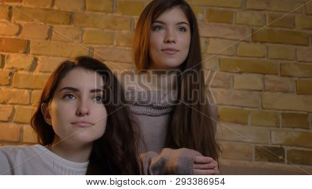 Closeup Bottom Up Portrait Of Two Young Pretty Women Watching Tv In A Cozy Apartment Indoors