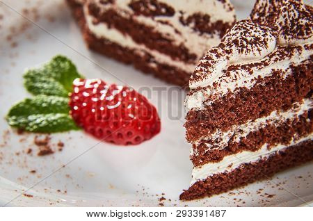 Chocolate Cake On A White Plate With Strawberries And Mint Close-up