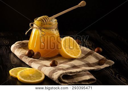 Honey With Nuts, Lemon And A Spoon For Honey On A Checked Tablecloth With Black Background