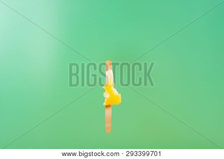 Yellow Popsicle With The Last Bit On A Light Green Background