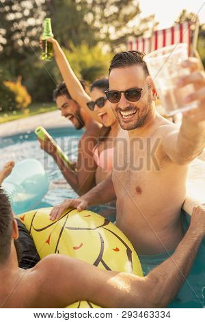Group Of Friends At A Poolside Summer Party, Having Fun In The Swimming Pool, Drinking Cocktails And
