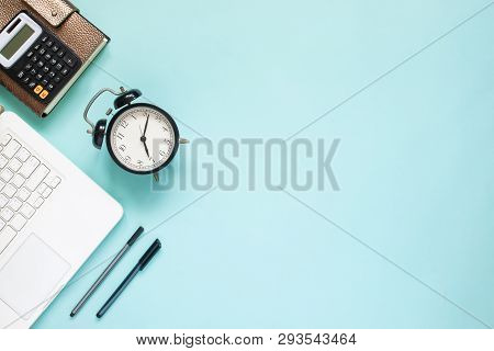 Creative Flat Lay Of Workspace Desk With Laptop,  Caculator And Notebook On Blue Colour Background. 