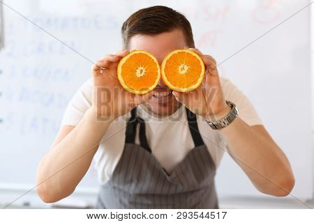 Man Holds Halves Of Cut Orange As Eye Glasses Portrait Background Concept