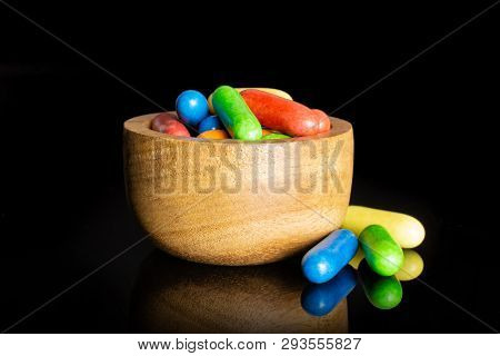 Lot Of Whole Sweet Licorice Comfit Closeup In A Wooden Bowl Isolated On Black Glass