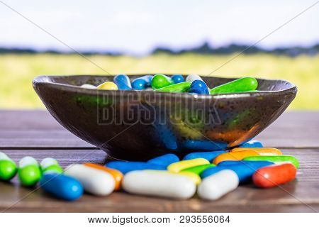 Lot Of Whole Sweet Licorice Comfit On Grey Ceramic Plate With Green Wheat Field In Background