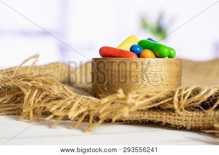Lot Of Whole Sweet Licorice Comfit In A Wooden Bowl On Jute Cloth With Flowers In A White Kitchen